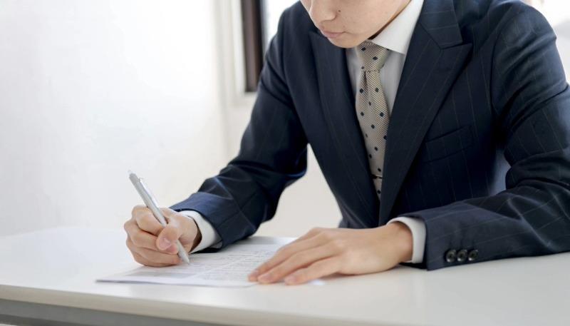 選考に必要な書類を書く男性の写真