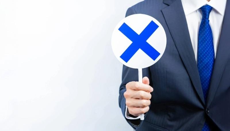 バツ印を持つ男性の写真