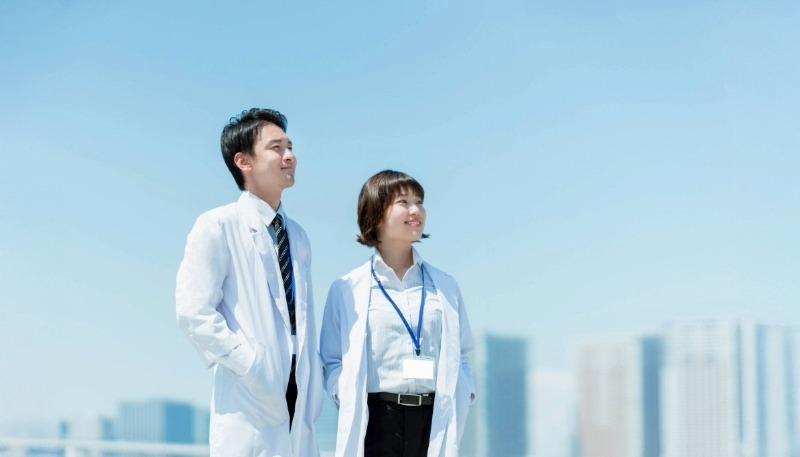 青空の下で空を見上げる男女の写真