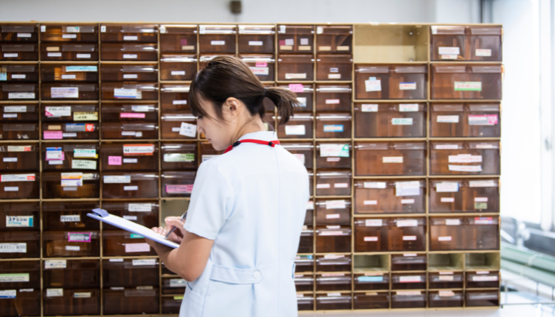 薬剤の棚を見る薬剤師