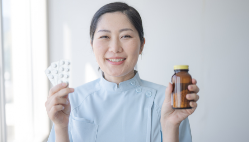 薬を持って微笑む薬剤師の様子