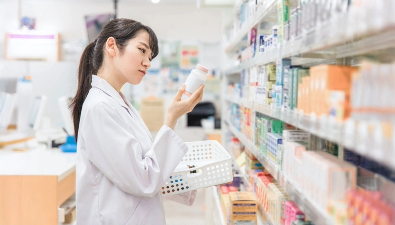 薬局内で薬の瓶に書かれた詳細を確認する薬剤師の写真