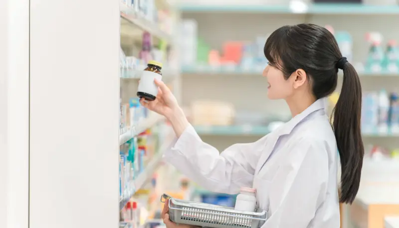 ドラッグストア薬剤師が調剤棚から薬を取る写真